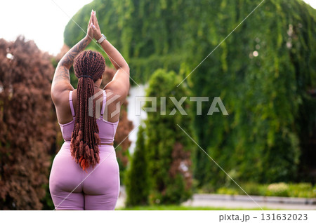 Long-haired woman in pink doing yoga outside and looking tranquil 131632023