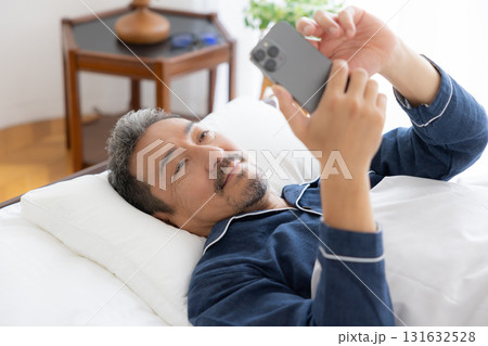 ベッドでスマホを見るミドル男性 131632528