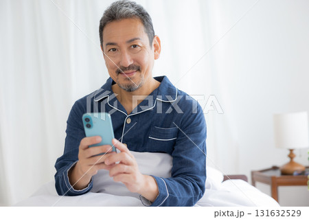 ベッドでスマホを見るミドル男性 131632529