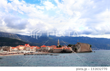 Old town, fortress wall and Adriatic sea, Budva, Montenegro. Beautiful scene with medieval houses and seascape. Topic of summer vacation, travel, cruises, tour Old town, fortress wall and Adriatic sea, Budva, Montenegro. Beautiful scene with medieval houses and seascape. Topic of summer vacation, travel, cruises, tour 131632770