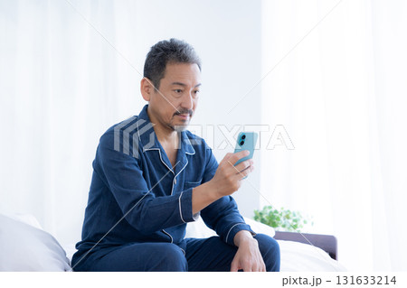 ベッドでスマホを見るミドル男性 131633214