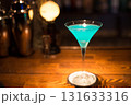 木製のバーカウンターに置かれた青いカクテル 131633316