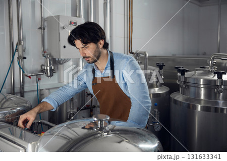 A man is wearing an apron and diligently working on a machine 131633341