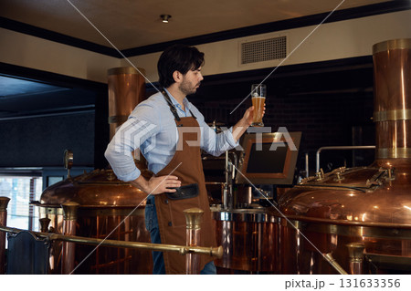 A man is taking in the aroma of a glass of beer in a brewery 131633356