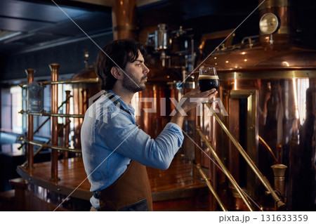 A man is holding a cold glass of beer inside a local brewery 131633359