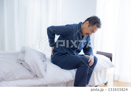 ベッドに腰をおさえるミドル男性 ベッドに腰をおさえるミドル男性 131633824