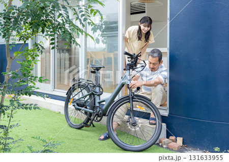 庭で電動自転車をメンテナンスをするミドル男性 131633955