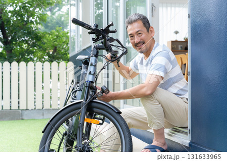 庭で電動自転車をメンテナンスをするミドル男性 131633965