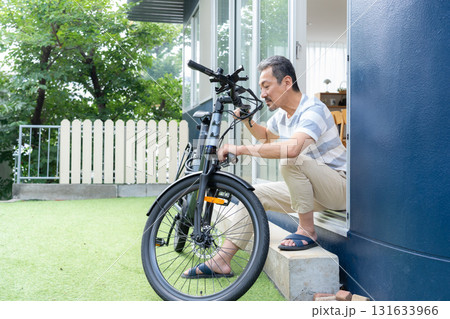 庭で電動自転車をメンテナンスをするミドル男性 131633966