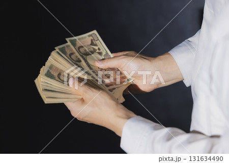 一万円札を数える作業服の男性 131634490