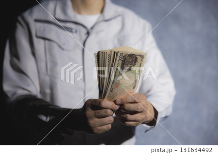 一万円札を数える作業服の男性 131634492
