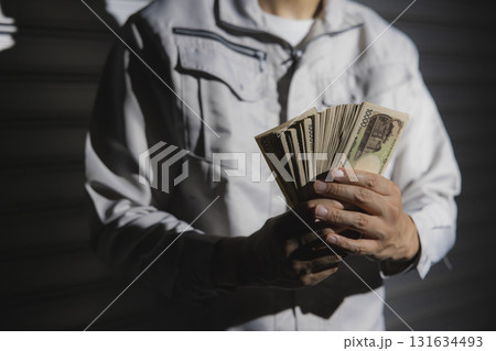 一万円札を数える作業服の男性 131634493