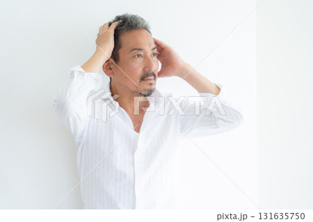 リビングでヘアケアをするミドルの男性 リビングでヘアケアをするミドルの男性 131635750