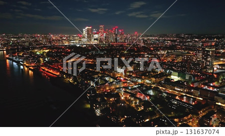 England, London: Breathtaking aerial view of London at night, featuring the illuminated Canary Wharf skyline, creating a mesmerizing cityscape reflecting in the River Thames. Drone flight England, London: Breathtaking aerial view of London at night, featuring the illuminated Canary Wharf skyline, creating a mesmerizing cityscape reflecting in the River Thames. Drone flight 131637074