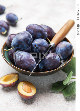 Fresh plums in bowl with knife on gray background 131637208