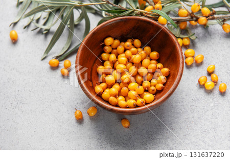 Sea buckthorn berries in wooden bowl on grey background 131637220