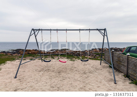 Empty children's swing on the seashore on a cloudy day 131637311