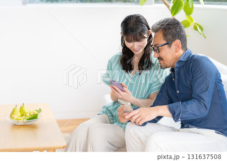 リビングでスマホを見るミドルの夫婦 リビングでスマホを見るミドルの夫婦 131637508