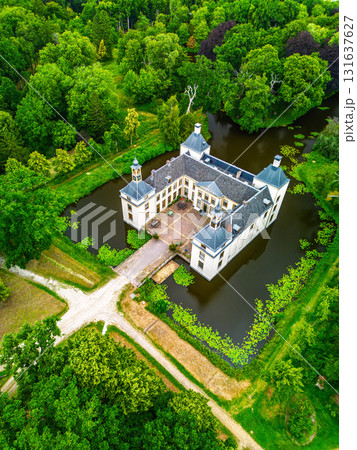 Aerial view of forested estate with symmetrical castle, moat, and bridge two front towers frame a central courtyard, blending historical architecture with lush natural surroundings. Aerial view of forested estate with symmetrical castle, moat, and bridge two front towers frame a central courtyard, blending historical architecture with lush natural surroundings. 131637627