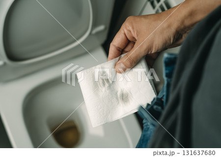 a man holding toilet paper after urinating 131637680