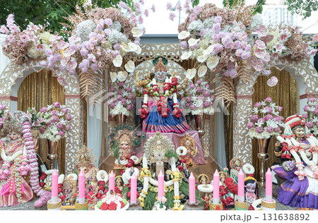 The statue of Sri Maha Lakshmi Devi or Ambabai is a Hindu goddess of wealth, prosperity and fortune with Other gods on a decorated platform with candles and an elaborate pink and white floral The statue of Sri Maha Lakshmi Devi or Ambabai is a Hindu goddess of wealth, prosperity and fortune with Other gods on a decorated platform with candles and an elaborate pink and white floral 131638892