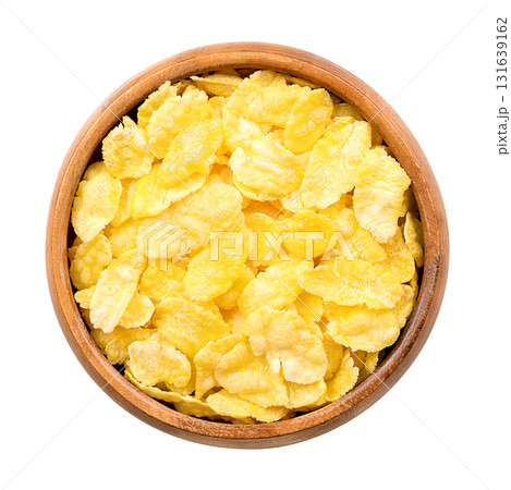 Corn flakes, or cornflakes in a wooden bowl. Breakfast cereal made from toasting flakes of corn or maize. Popular food item in American diet and in the United Kingdom. Isolated from above, food photo. Corn flakes, or cornflakes in a wooden bowl. Breakfast cereal made from toasting flakes of corn or maize. Popular food item in American diet and in the United Kingdom. Isolated from above, food photo. 131639162
