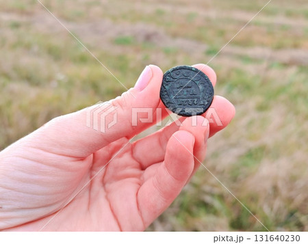 Old copper coin from 1737 in a man's hand. Ancient copper coin in hand of a treasure hunter 131640230
