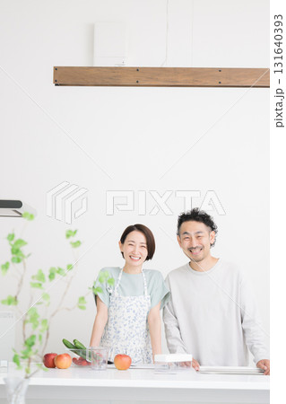 キッチンで笑顔のカメラ目線のミドル夫婦 131640393