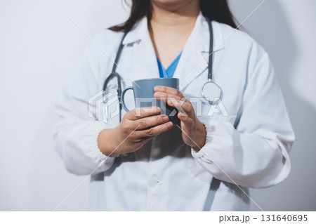 Portrait of Asian doctor woman standing holding coffee cup in white studio background Portrait of Asian doctor woman standing holding coffee cup in white studio background 131640695