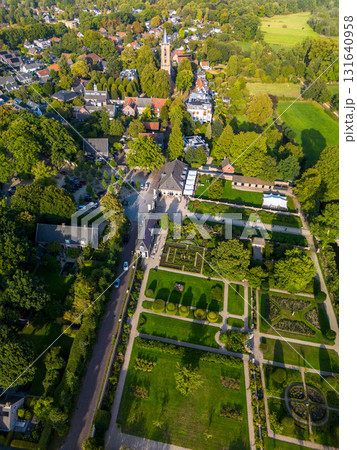 Aerial view of picturesque town with tall steeple church, formal garden, tree lined streets, and historic buildings showcasing harmony between architecture and natural design. 131640958