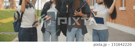 Happy students walking together on university campus, chatting and laughing outdoors after classes 131642220
