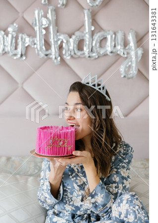 Young woman wearing crown eating birthday cake Young woman wearing crown eating birthday cake 131643381