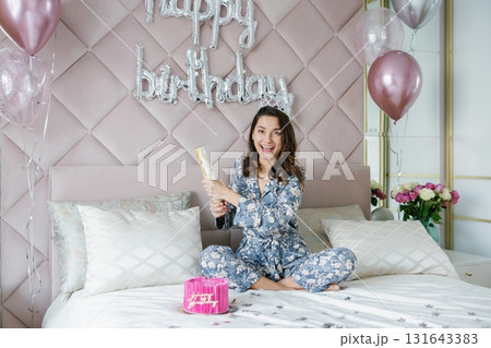 Young woman celebrating birthday opening firecracker on bed Young woman celebrating birthday opening firecracker on bed 131643383