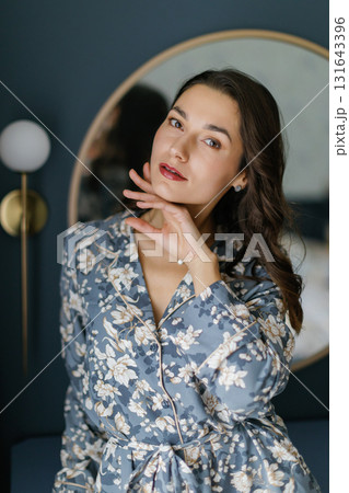 Woman wearing pajamas posing in elegant bedroom with blue walls 131643396