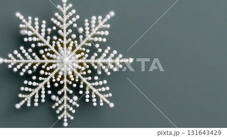 A delicate white beaded snowflake deco n on a solid grey background 131643429