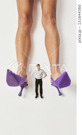 Surreal collage art. Tiny man standing between woman purple heels in confident pose Surreal collage art. Tiny man standing between woman purple heels in confident pose 131644360