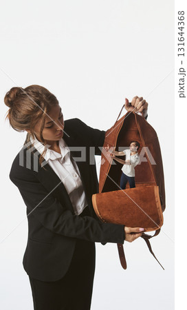Contemporary collage. Woman holding open bag with tiny man inside reaching out 131644368