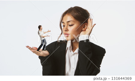 Woman listening to tiny man standing on her palm with thoughtful expression 131644369