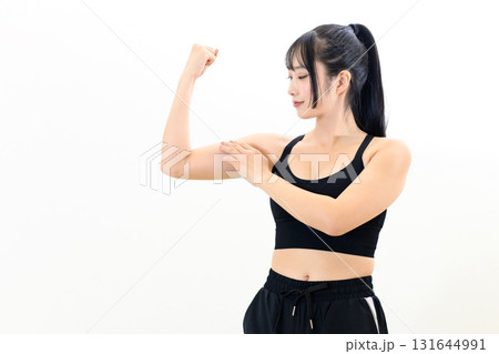 体を鍛えてるかっこいい女性　力こぶをつくる　筋トレ女子　スポーツブラ　白バック　トリミングアップ 131644991
