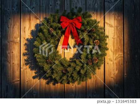 Rustic Farmhouse Christmas Wreath with a Red Bow on a Weathered Barn Wood Door at Sunset 131645383