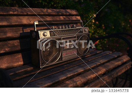Vintage ghetto blaster rests on weathered bench with sunlit chrome details Vintage ghetto blaster rests on weathered bench with sunlit chrome details 131645778