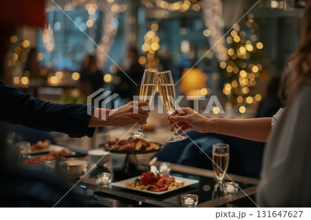 Two colleagues clink champagne glasses in festive office lounge holiday celebration Two colleagues clink champagne glasses in festive office lounge holiday celebration 131647627