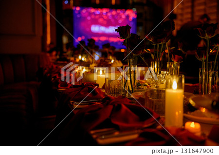 Close-up of a long table with flowers and burning candles in a dark room Close-up of a long table with flowers and burning candles in a dark room 131647900