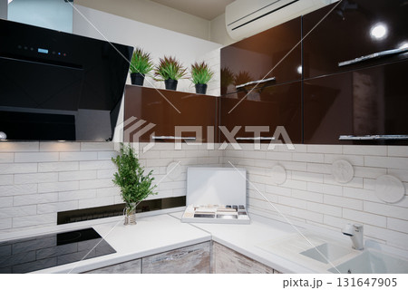A trendy kitchen with white countertops, an induction hob, and spotlights A trendy kitchen with white countertops, an induction hob, and spotlights 131647905