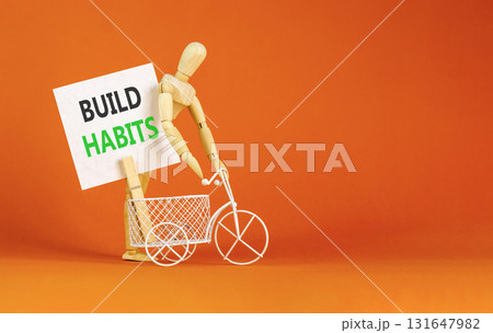 Build habits symbol. Concept word Build habits on beautiful white paper. Beautiful wooden clothespin. Businessman's model. Beautiful orange background. Business build habits concept. Copy space. 131647982