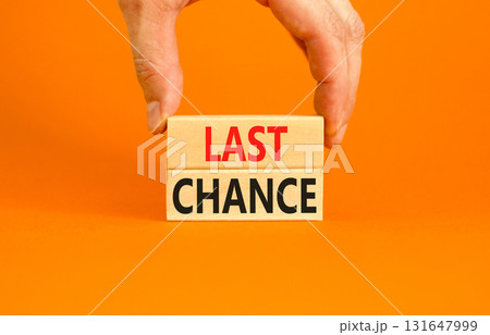 Last chance symbol. Concept word Last chance on beautiful wooden blocks. Beautiful orange paper background. Businessman's hand. Business last chance concept. Copy space. 131647999
