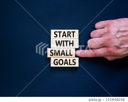 Start with small goals symbol. Concept words phrase Start with small goals on beautiful wooden blocks. Beautiful black background. Businessman's hand Business Start with small goals concept Copy space Start with small goals symbol. Concept words phrase Start with small goals on beautiful wooden blocks. Beautiful black background. Businessman's hand Business Start with small goals concept Copy space 131648036