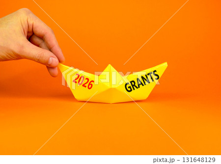 2026 Grants symbol. Concept words 2026 Grants on beautiful yellow paper boat. Beautiful orange paper background. Businessman's hand. Business and 2026 grants concept. Copy space. 2026 Grants symbol. Concept words 2026 Grants on beautiful yellow paper boat. Beautiful orange paper background. Businessman's hand. Business and 2026 grants concept. Copy space. 131648129
