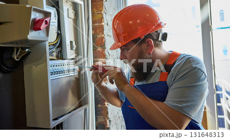 Electrician repairing industrial control panel with focus and precision 131648313
