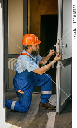Technician fixing metal door lock in modern office building Technician fixing metal door lock in modern office building 131648338